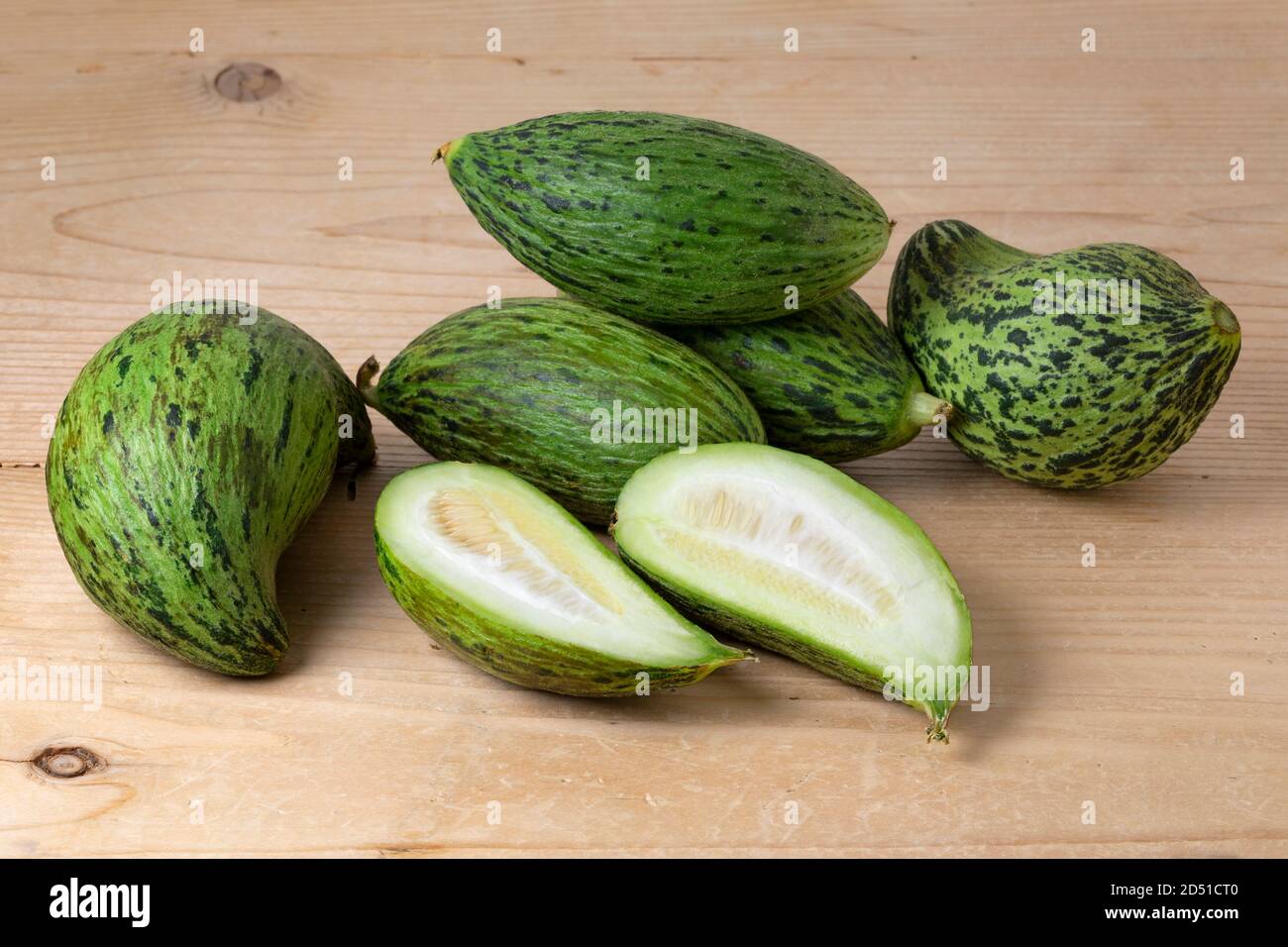 Frische ganze und halbierte Kelek Frucht, unreife Melone, auf Holzhintergrund Nahaufnahme Stockfoto