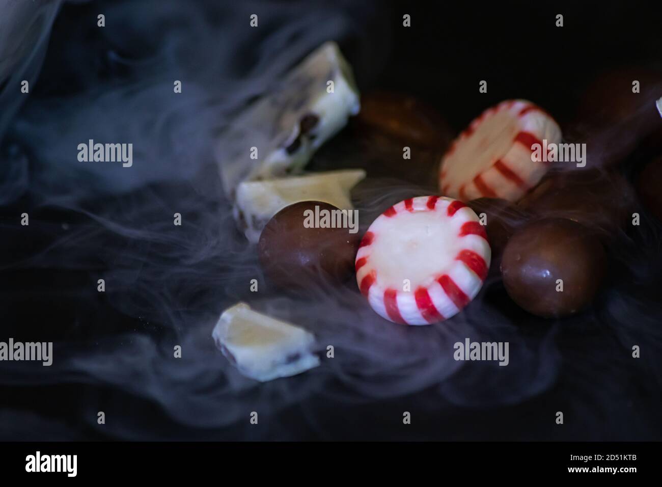Verschiedene Pralinen und Halloween Bonbons auf schwarzem Hintergrund mit Trockener Eisrauch Stockfoto