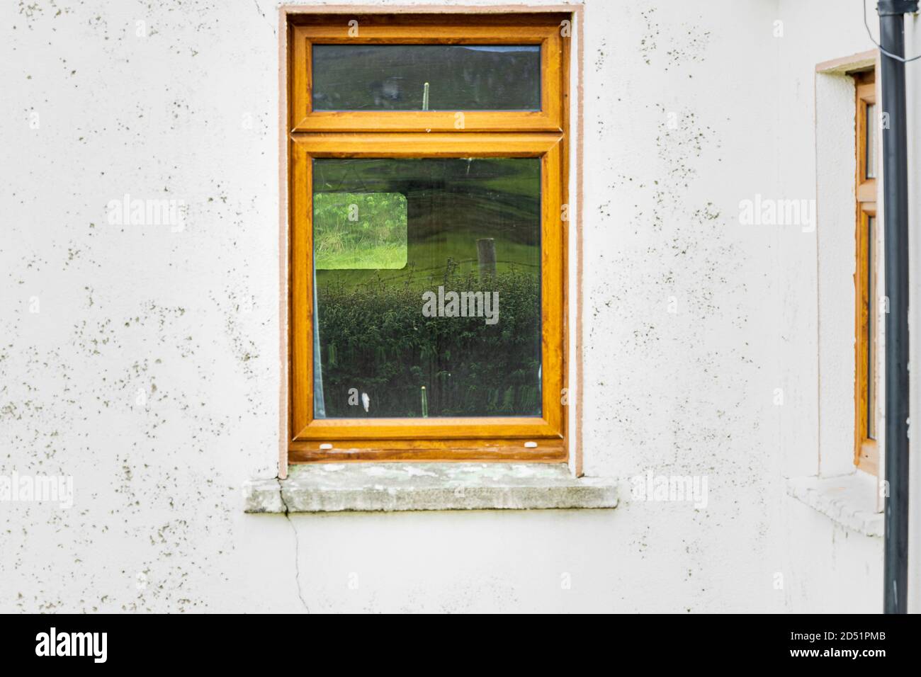 Spiegelung in einem Spiegel der grünen Felder und im Glas des Fensters eines alten Häuschens entlang der Killeen-Schleife Spaziergänge in der Nähe von Louisburgh, Grafschaft Mayo, Stockfoto
