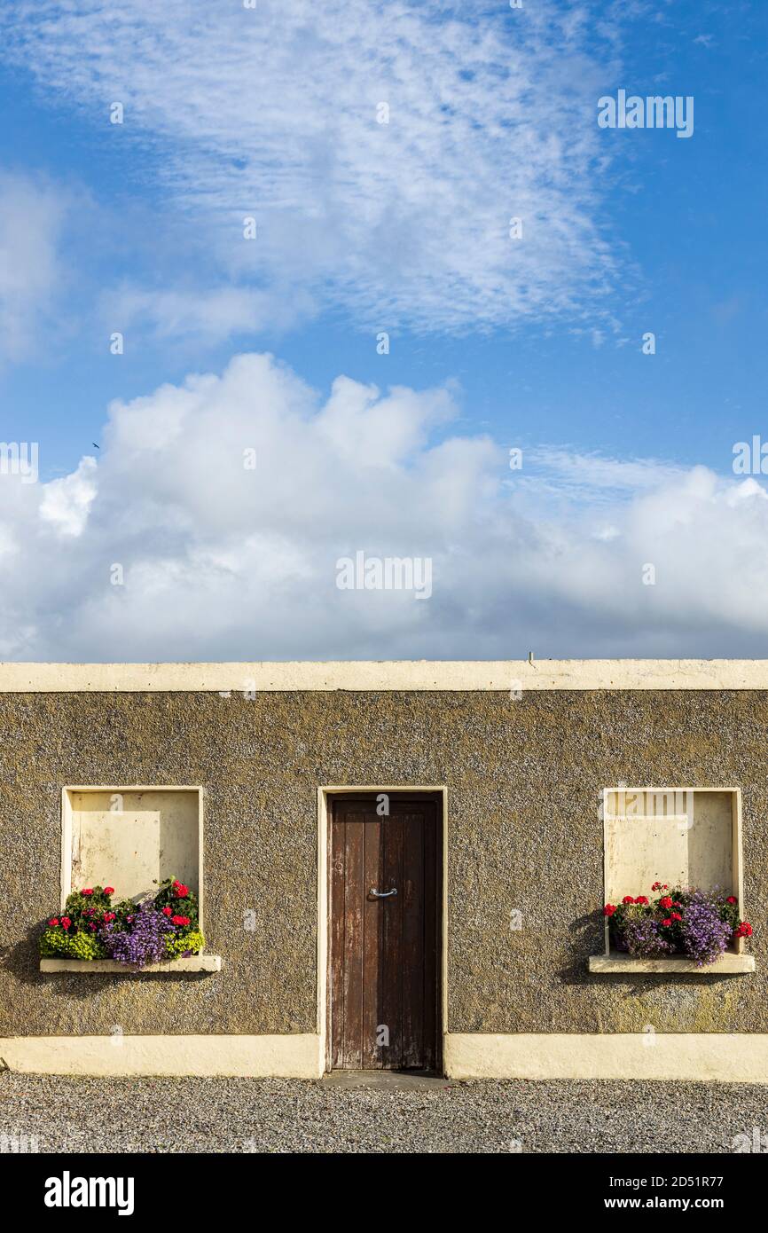 Altes Haus mit gemauerten Fenstern, die mit blühenden Fensterkästen dekoriert sind, entlang der Killeen-Rundwanderung in der Nähe von Louisburgh, County Mayo, Irland Stockfoto