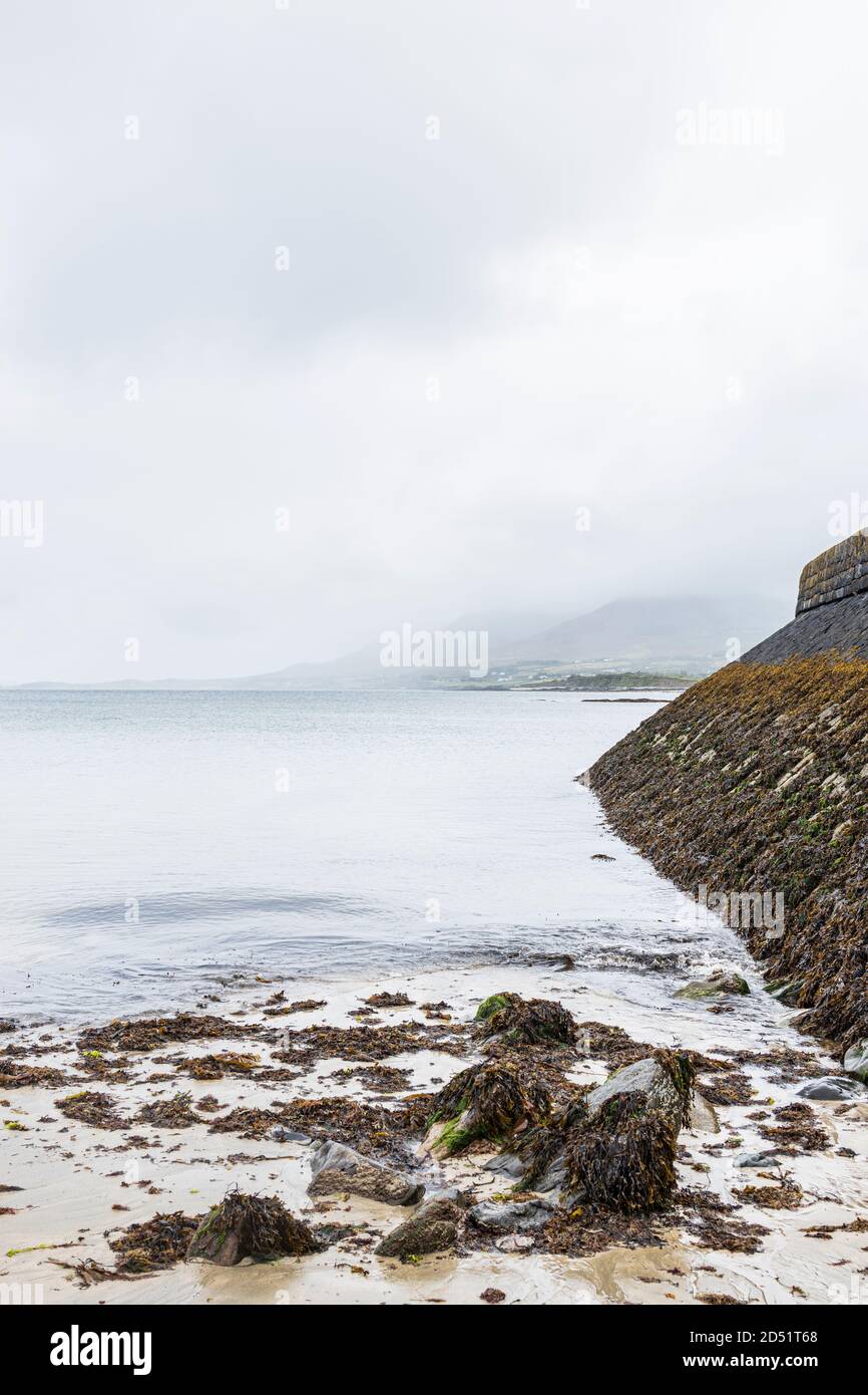 Blick entlang der Pier Wand auf Meereshöhe an einem ruhigen nebligen Tag in Old Head, Louisburgh, County Mayo, Irland Stockfoto