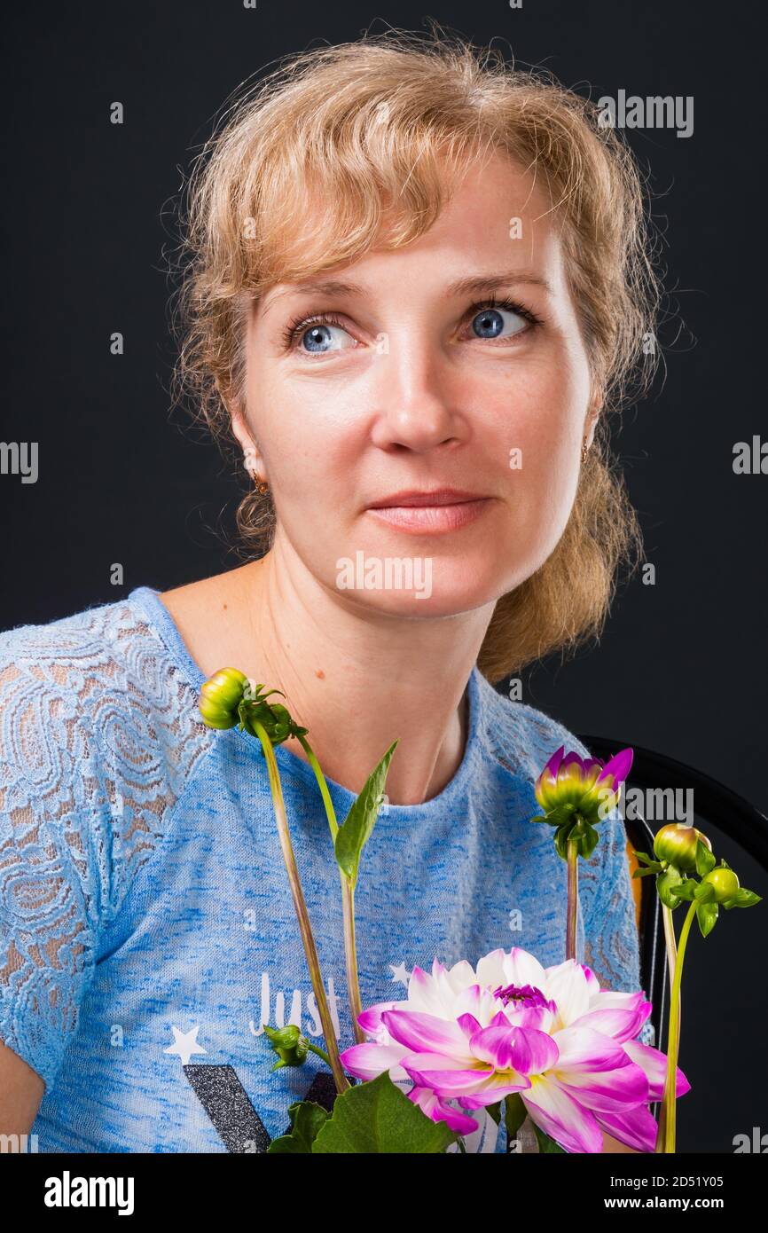 Zarte nachdenkliche Frau 45 Jahre alt mit Blumen Stockfoto