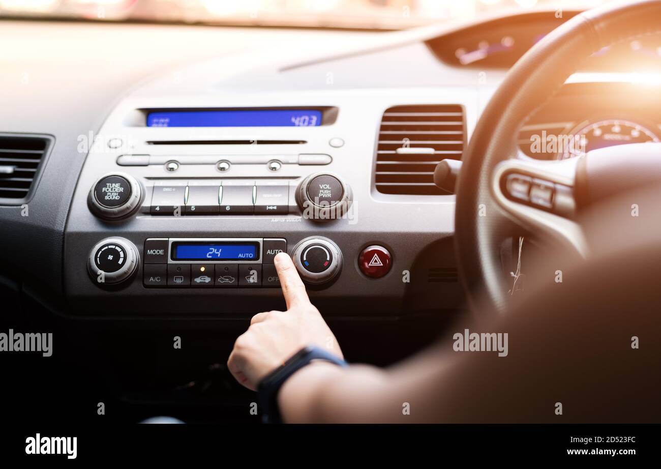 Frau drücken Sie die Klimaanlage im Auto an Stockfoto