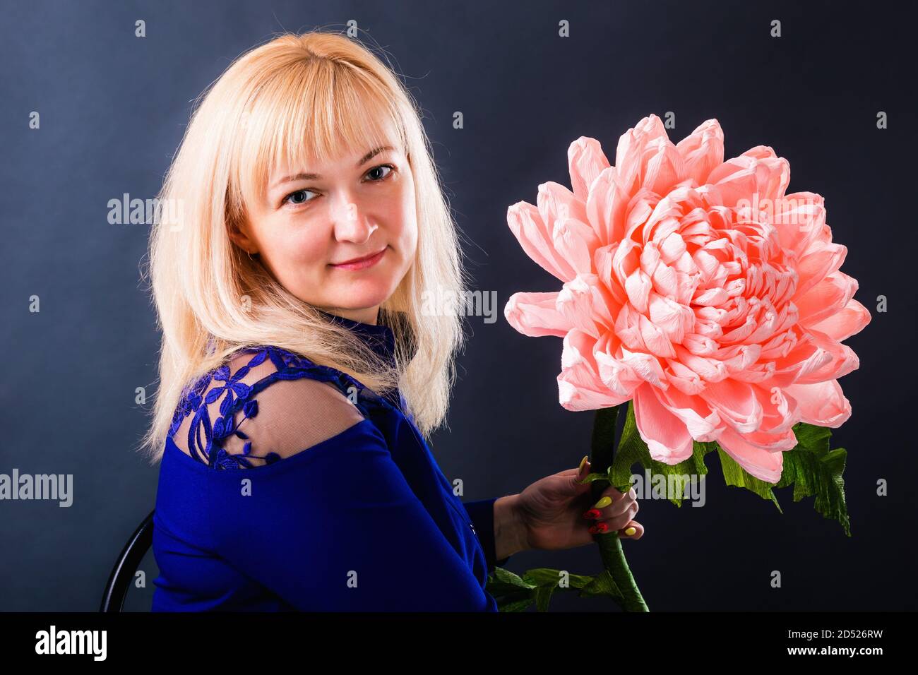 Frau zeigt eine riesige rosa Blume Hand aus Papier. Stockfoto