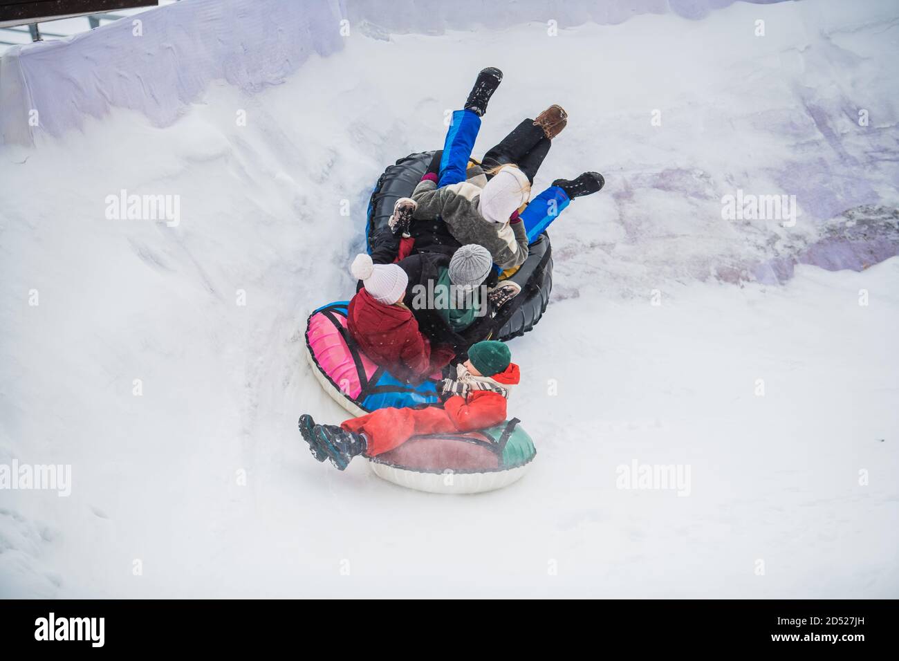 Die Eltern kauften ihre Kinder Tubing und nun fährt die ganze Familie die Eisrutsche hinunter. Stockfoto