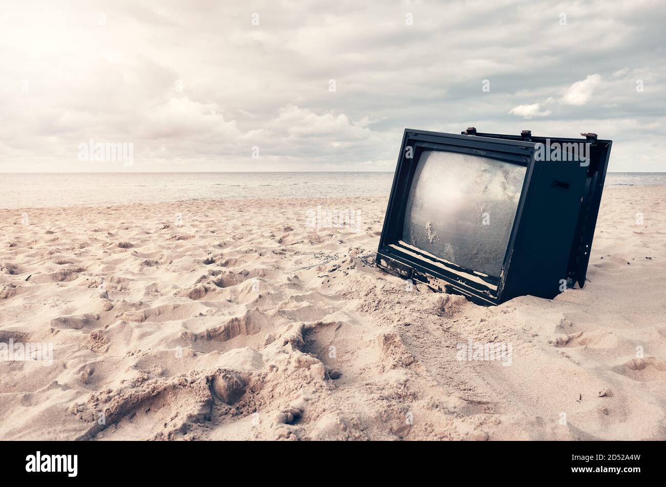 Altes kaputtes Fernsehgerät an einem Strand bei Sonnenuntergang, selektiver Fokus. Stockfoto