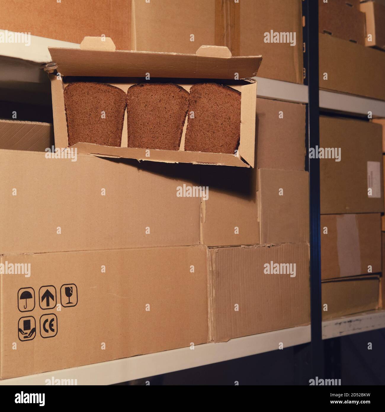 Lagerhaus mit offenen Kisten mit Lebensmitteln. Diebstahl von Brot in einem Postlager während der Quarantäne durch Coronavirus Stockfoto