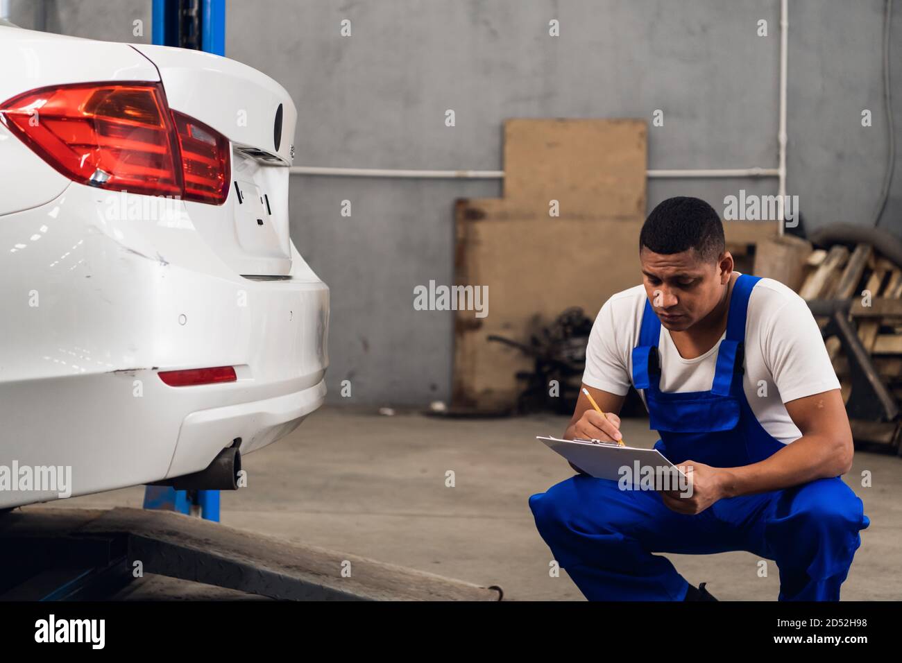Ein Mechaniker in Arbeitskleidung inspiziert ein Auto in einem Werkstatt  Stockfotografie - Alamy