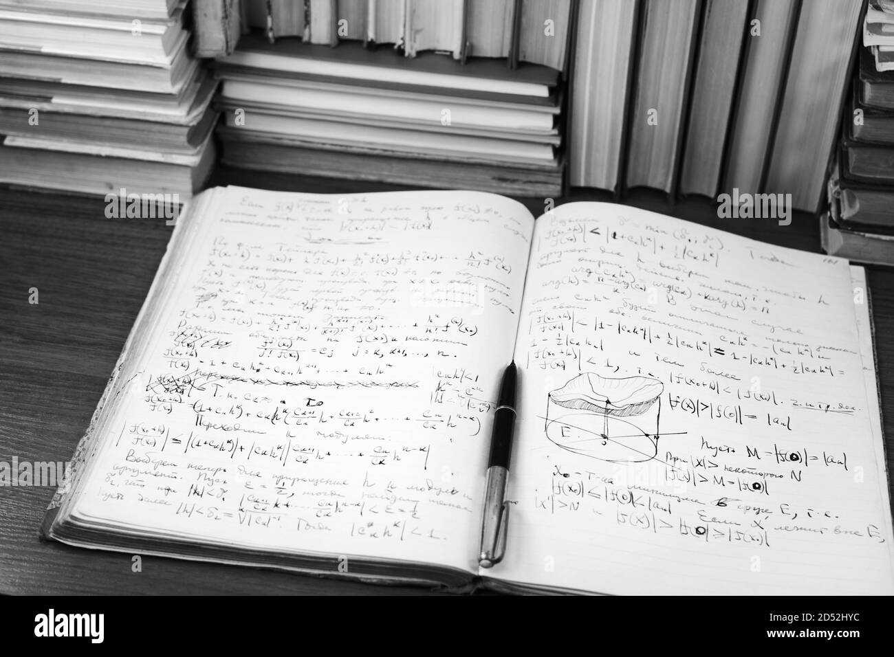 Offenes Schreibbuch mit mathematischen Vorträgen vor dem Hintergrund von Büchern Stockfoto