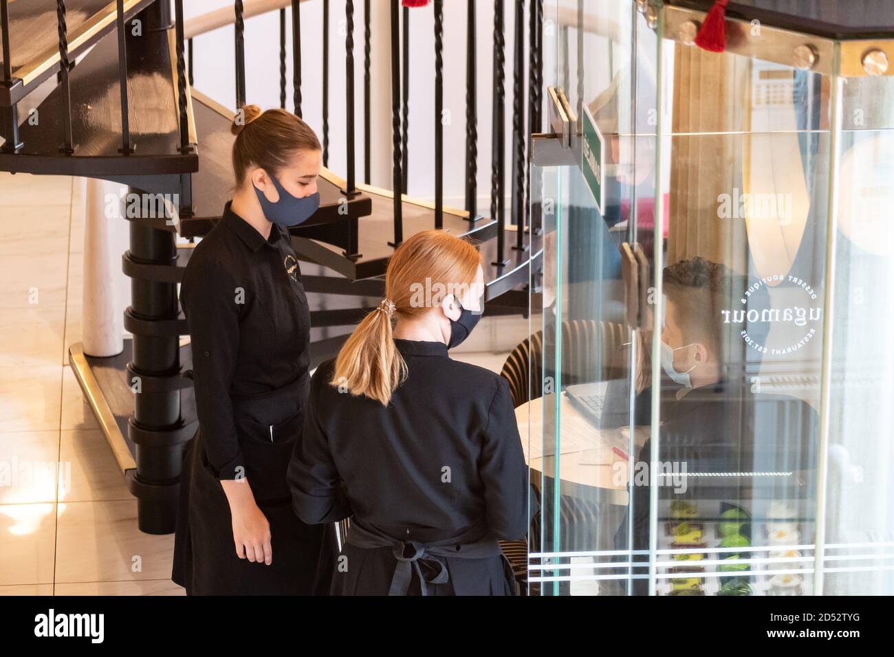Kellnerinnen mit Masken kontrollieren oder überprüfen die Gäste an der Bar, Café oder Restaurant Eingang in der Nähe der Tür Stockfoto