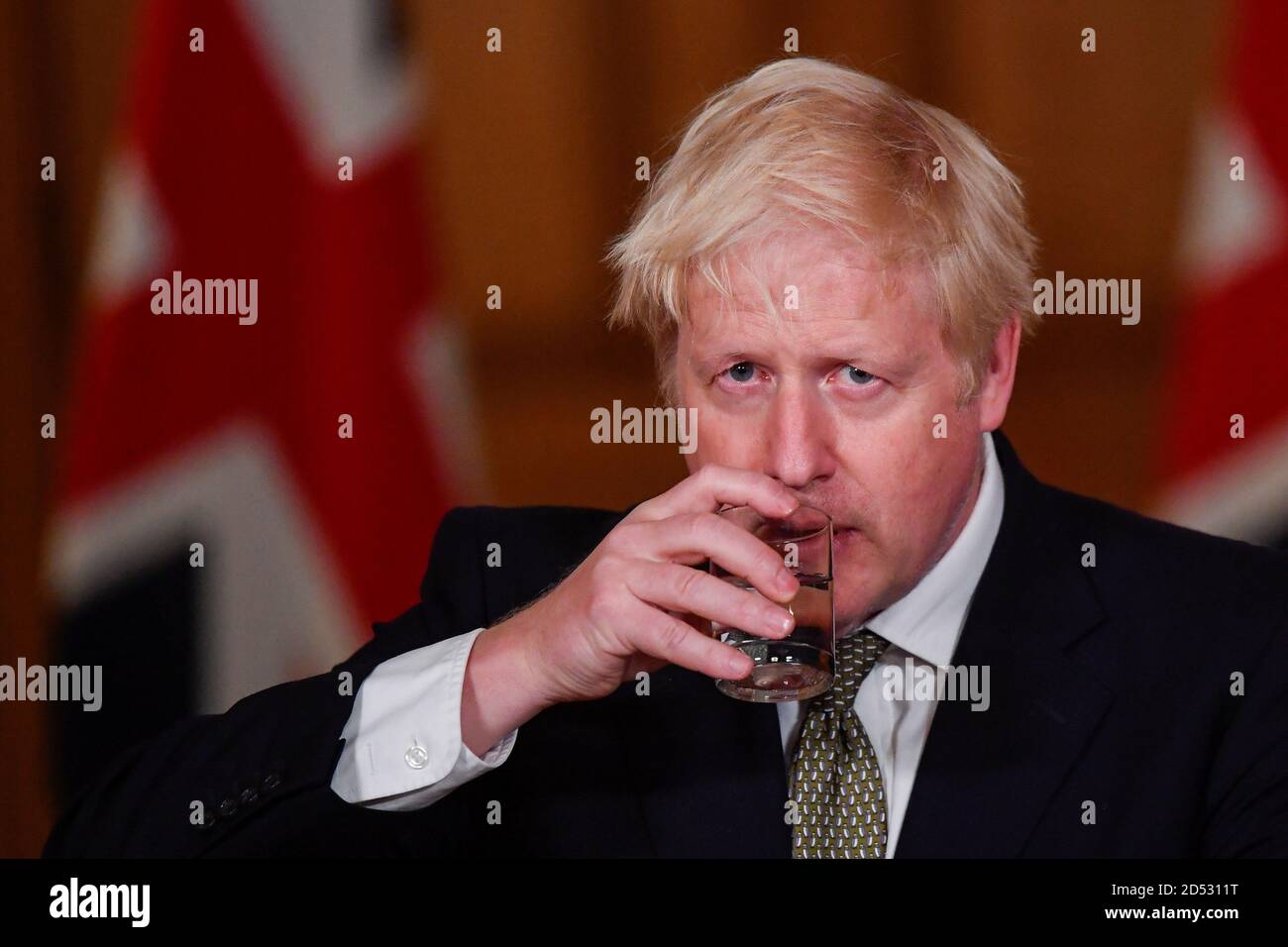 Premierminister Boris Johnson trinkt Wasser während einer Medienbesprechung in Downing Street, London, über das Coronavirus (COVID-19). Stockfoto