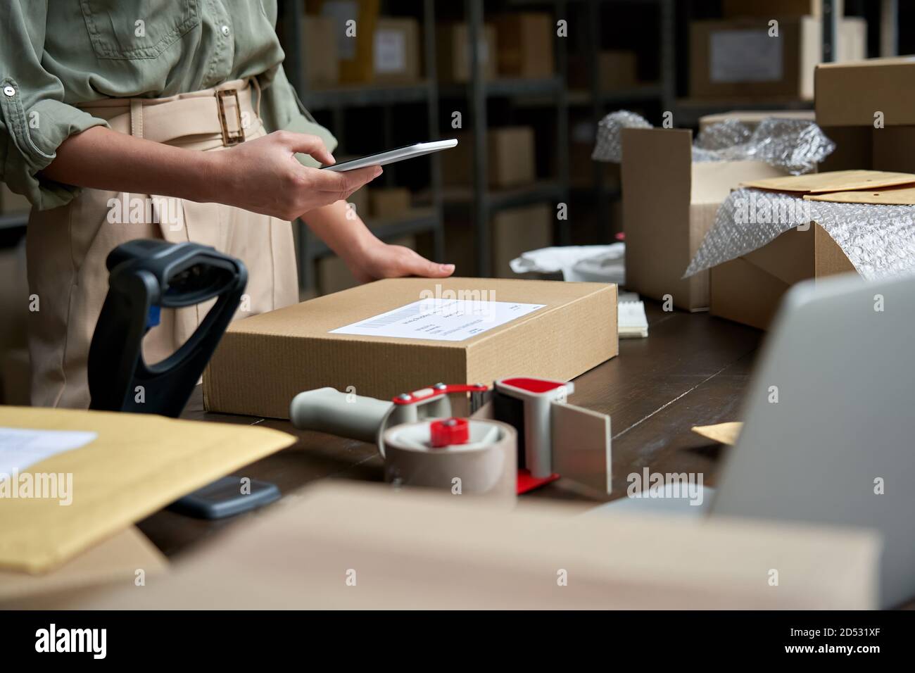 Weibliche Kleinunternehmerin, die die mobile App auf dem Smartphone verwendet, um die Paketbox zu überprüfen. Stockfoto