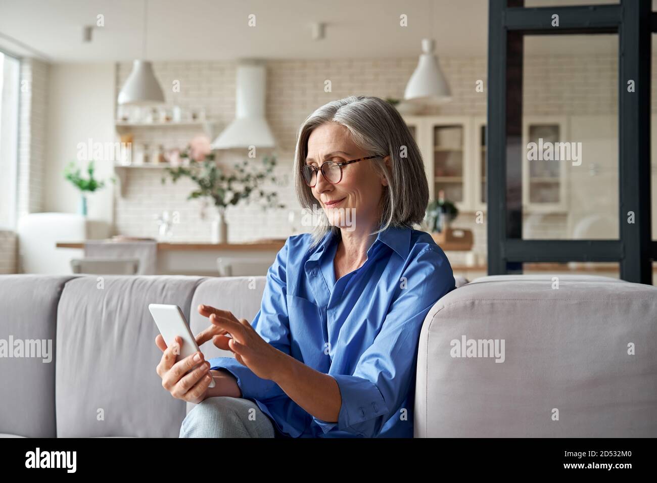 Ältere alte ältere Frau mit Smartphone sitzen auf dem Sofa zu Hause. Stockfoto