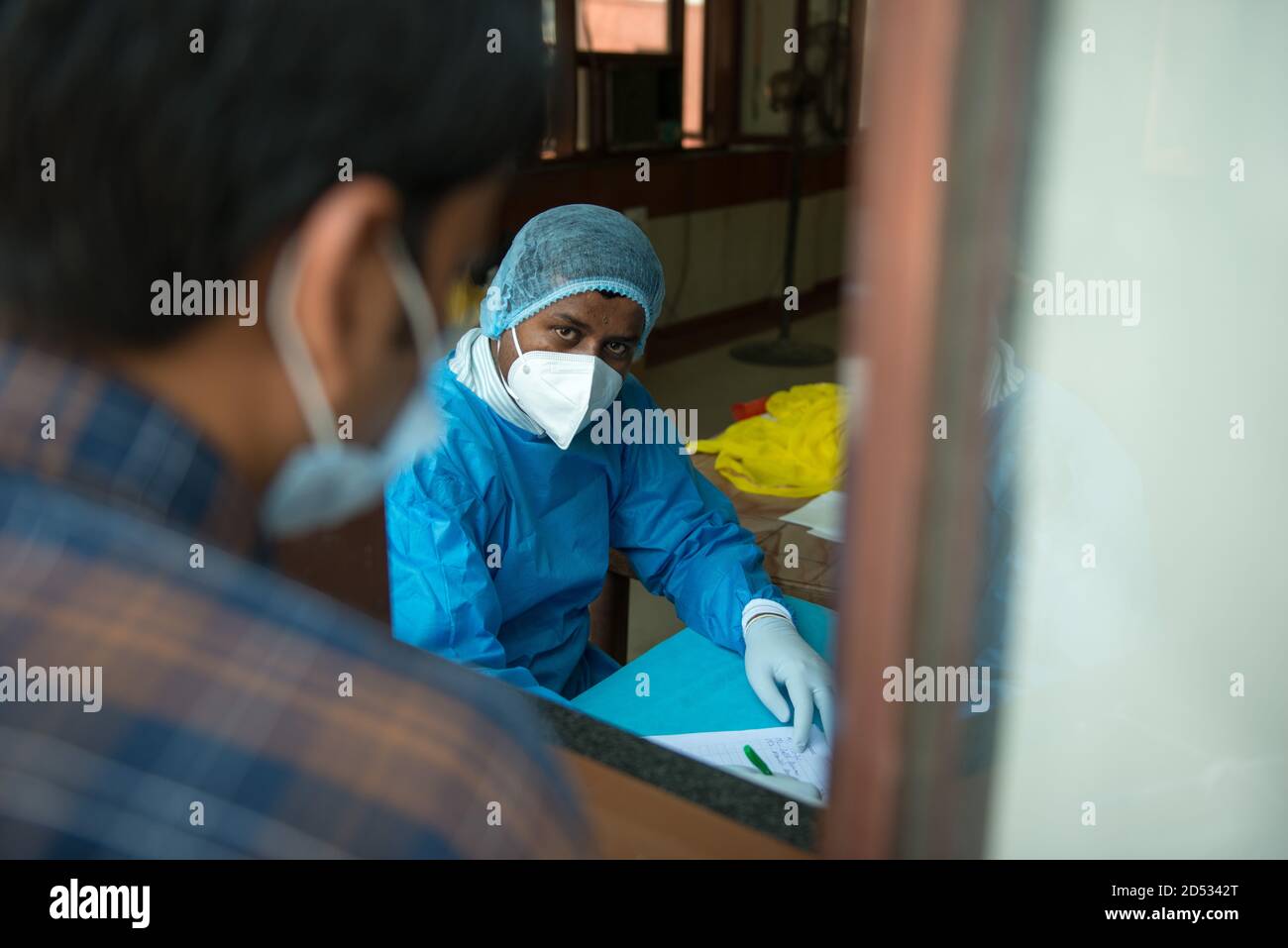 Ein Gesundheitshelfer, der einen Anzug für persönliche Schutzausrüstung trägt, wird gesehen, wie er die Mitglieder registriert, die den Covid-19-Test machen.Indien ist nach den Vereinigten Staaten das am zweithäufigsten von Coronavirus betroffene Land der Welt.die Regierung hat weitere Covid-19-Schnellantigen-Tests in Indien eingerichtet. Stockfoto