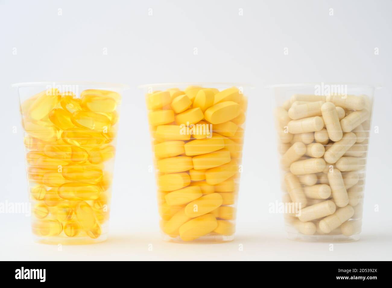 Gesunde Ernährung Konzept der drei Plastikbecher mit Pillen Softgels Omega3 Kapsel Vitamine Tabletten auf weißem Hintergrund mit Kopie Platz Stockfoto
