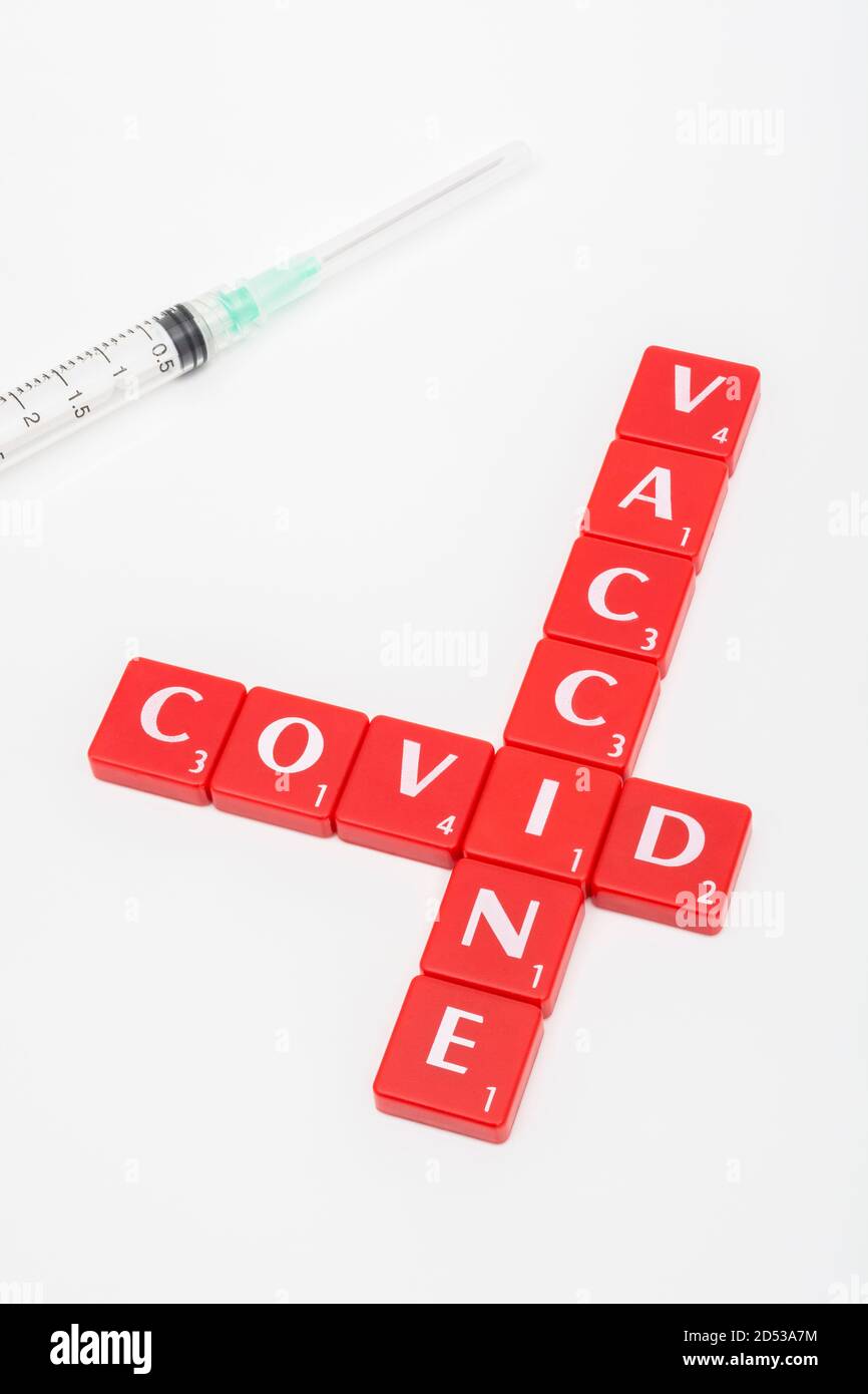 Kachelmatrix mit rotem Buchstaben für Covid 19, Aushärten von Covid, & Coronavirus / Covid-Impfstoff & Spritzen auf off-white Hintergrund. Für den gefürchteten Covid 19. Stockfoto