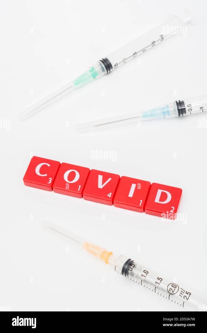 Kachelmatrix mit rotem Buchstaben für Covid 19, Aushärten von Covid, & Coronavirus / Covid-Impfstoff & Spritzen auf off-white Hintergrund. Für den gefürchteten Covid 19. Stockfoto