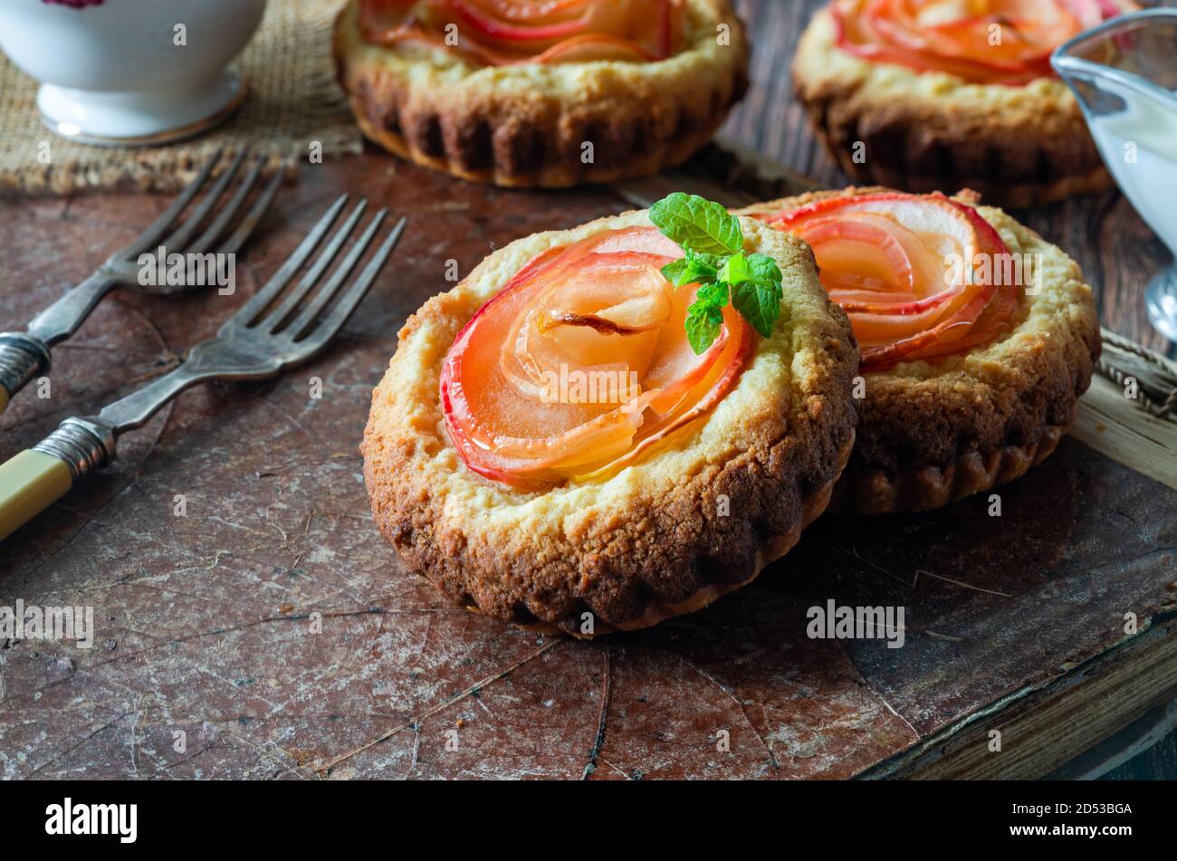 Mini Mandeltörtchen mit Apfelscheiben in einer Rose angeordnet Stockfoto