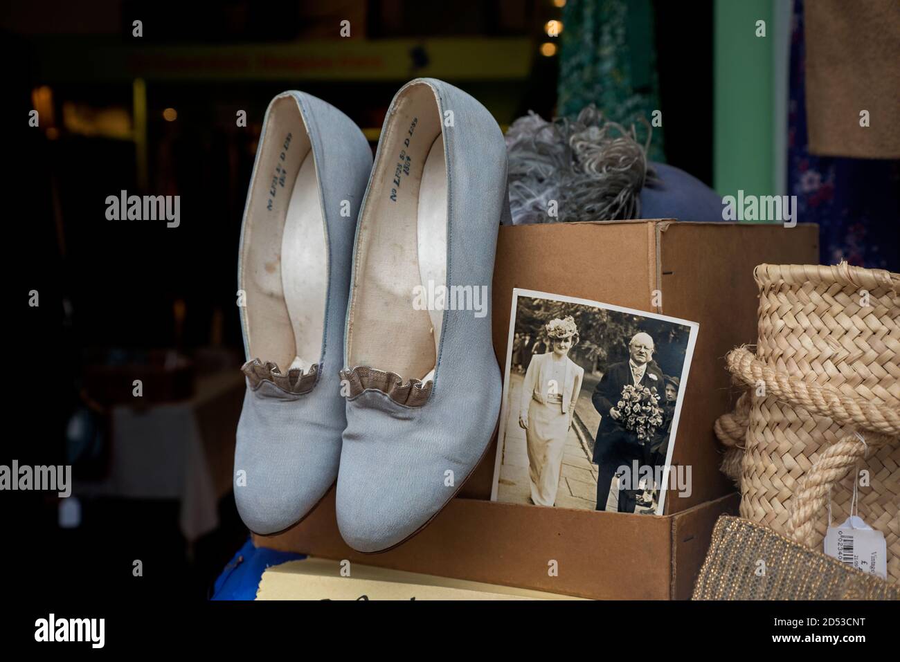 Blasse blaue Schuhe und ein altes Foto im Fenster eines Wohltätigkeitsladens in Edinburgh, Schottland, Großbritannien. Stockfoto