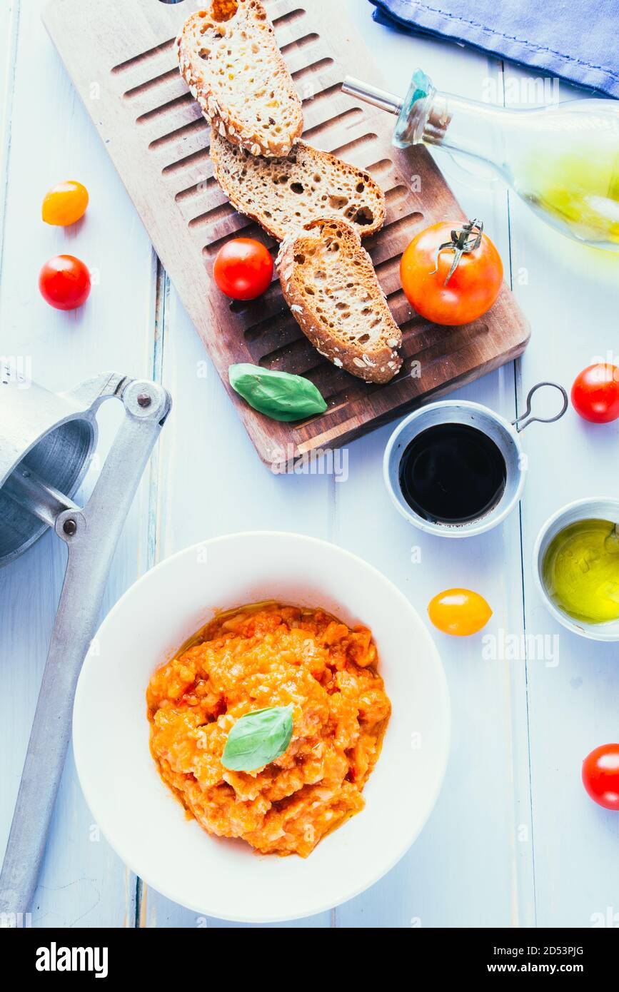 Pappa al Pomodoro (Brot- und Tomatensuppe, Italien) mit roten Zwiebeln und Basilikum, auf einem weißen Gericht, Draufsicht, natürliches Licht. Stockfoto