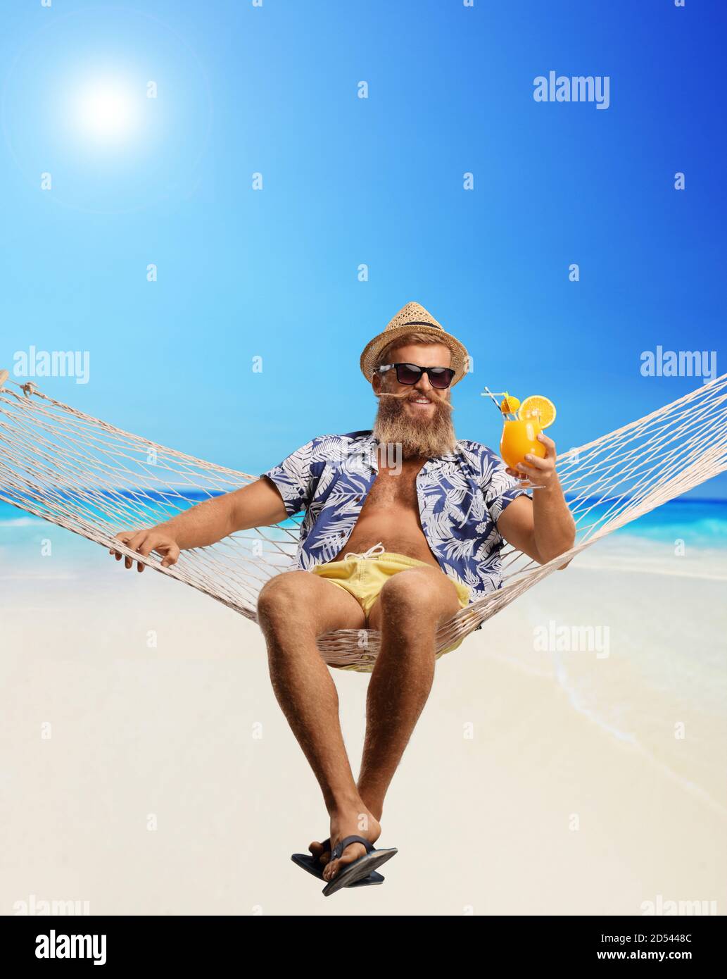 Blonde bärtige Kerl sitzt auf einer Hängematte Schaukel mit einem Cocktail am Strand Stockfoto