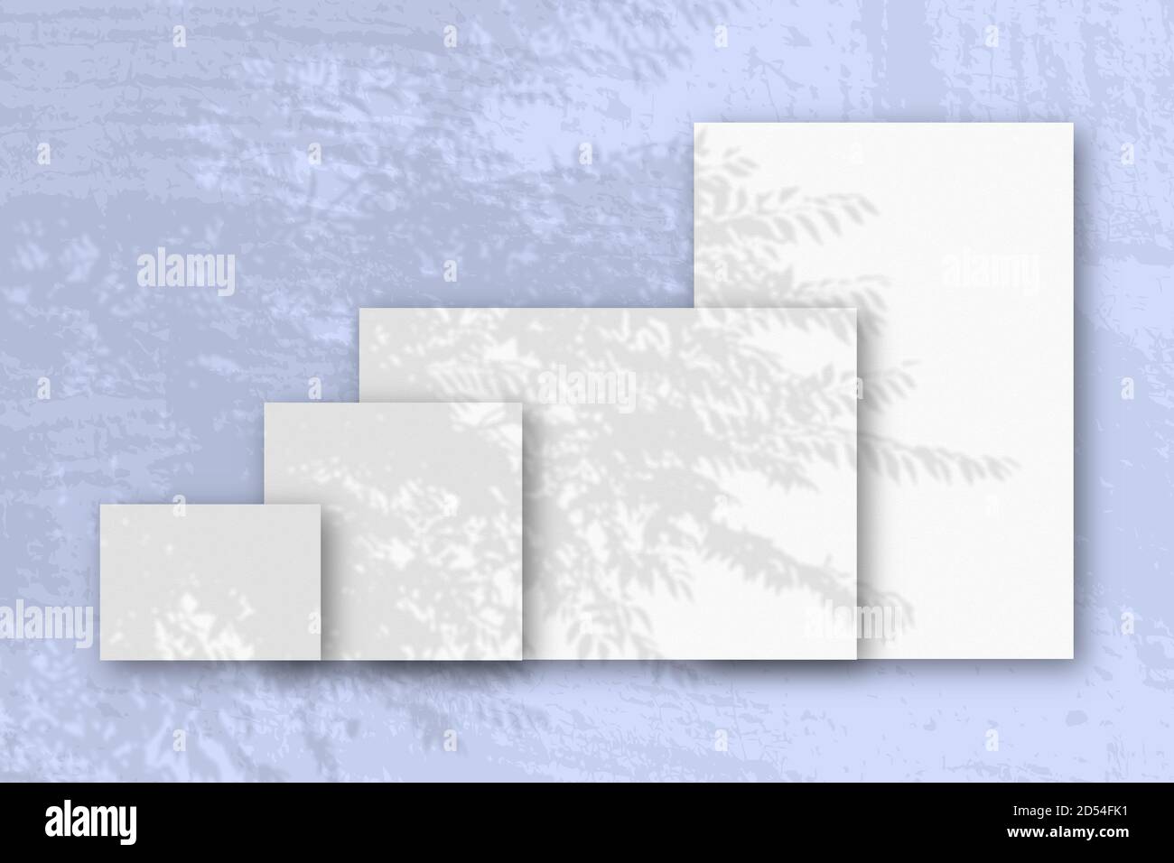 Mehrere horizontale und vertikale Blätter aus weißem strukturiertem Papier vor einem blauen Wandhintergrund. Mockup mit einer Überlagerung von Pflanzenschatten. Tageslicht Stockfoto