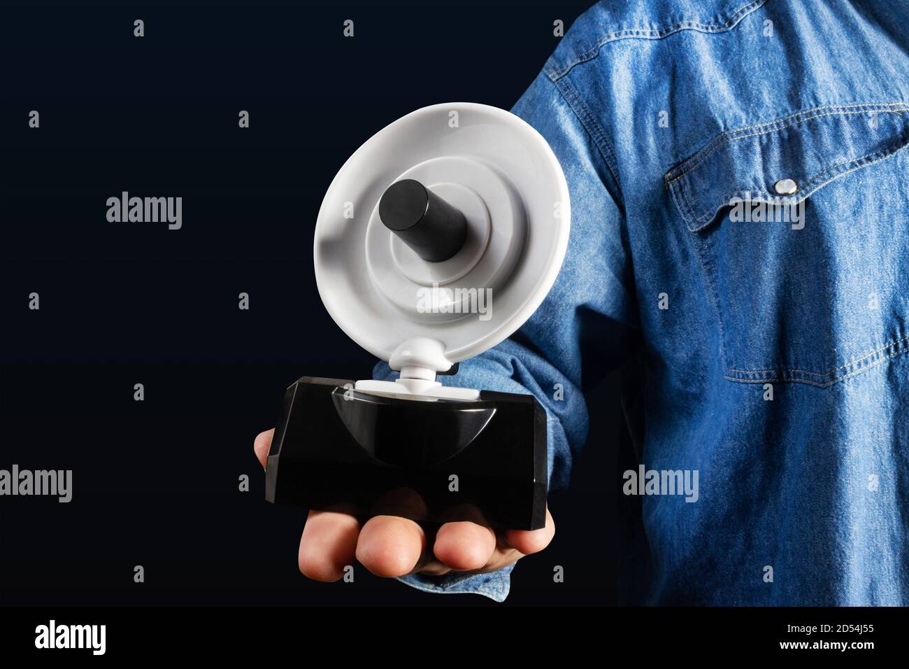 Foto von männlicher Hand in Jeans-Hemd mit kleiner Satelliten-Antenne. Stockfoto