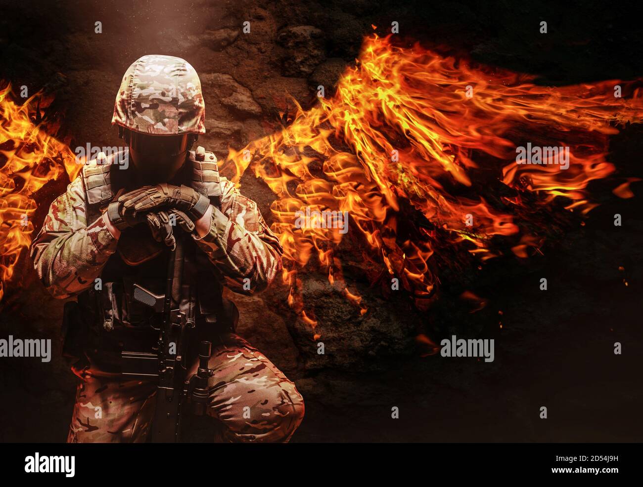 Foto eines voll ausgerüsteten Soldaten in Helm, Panzerweste und Gewehr knieend mit Feuerflügeln hinter ihm. Stockfoto