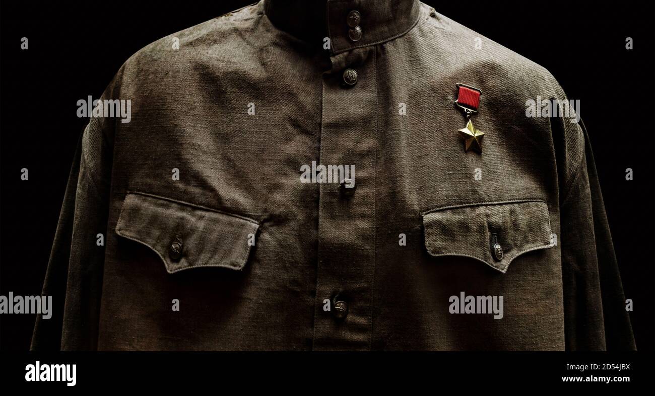 Foto von einem sowjetischen 2-Soldaten-Hemd auf schwarzem Hintergrund mit goldener Sternmedaille des Helden. Stockfoto