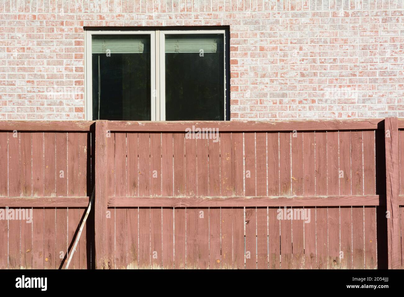 Texturierter Hintergrund von braun verwitterten Holzzaun und Ziegelwand Mit offenem Fenster mit Jalousien Stockfoto