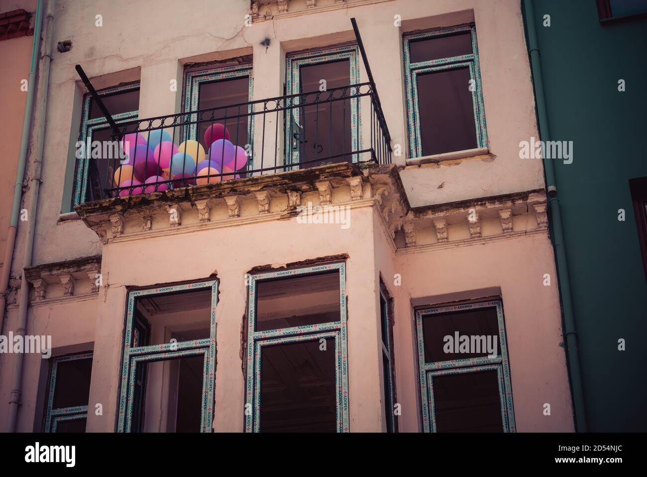 Schöne Aufnahme eines braunen Balkons mit bunten Luftballons Stockfoto
