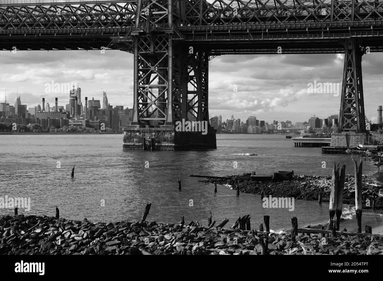 Blick auf Manhattan über den East River unter der Williamsburg Bridge, die Brooklyn mit Manhattan verbindet. Monotone Schwarzweißfotos. New York Stockfoto