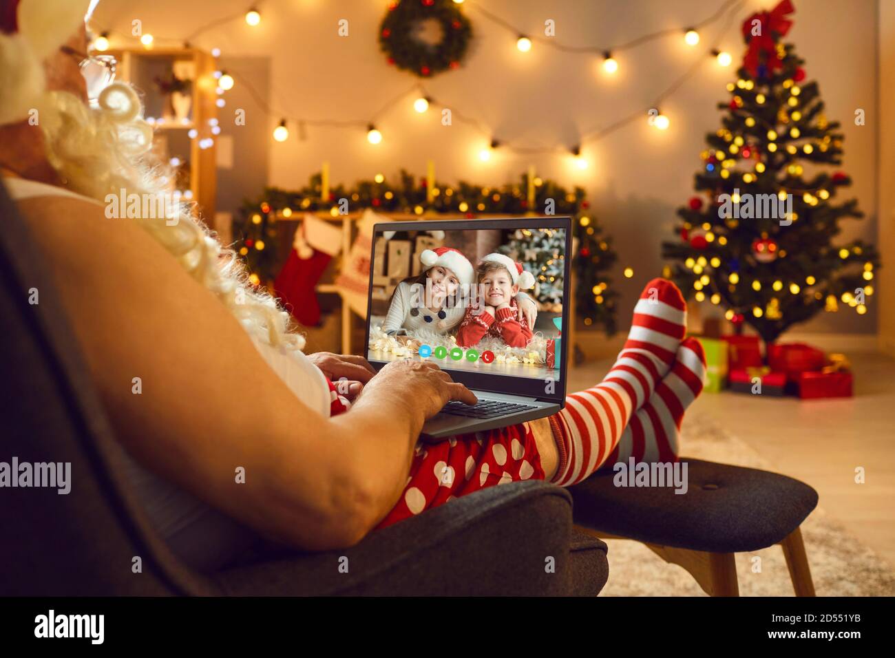 Weihnachtsmann in Kostüm mit weißem Bart chatten mit Enkeln online Auf dem Laptop während der Videoaufzeichnung Stockfoto