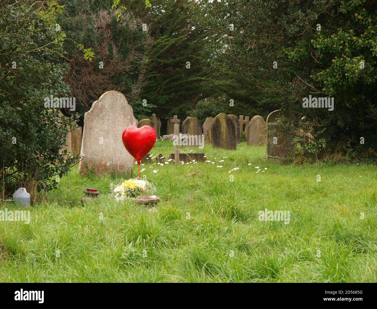 Roter herzförmiger Ballon in einem Friedhof Stockfoto