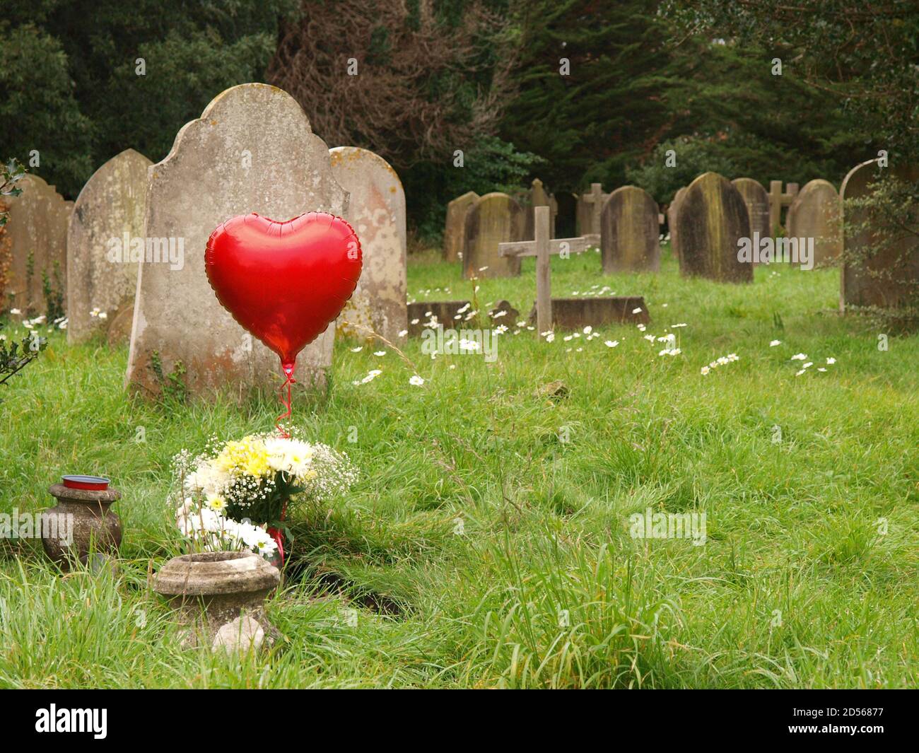 Roter herzförmiger Ballon in einem Friedhof Stockfoto