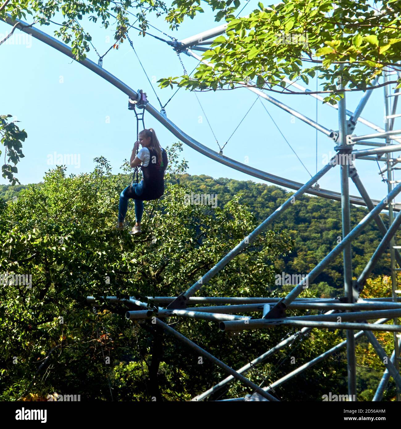 Bad Harzburg, Deutschland, 14. September 2020: Junge Frau mit langen blonden Haaren hängt von der Baumhängebahn über den Baumkronen Stockfoto