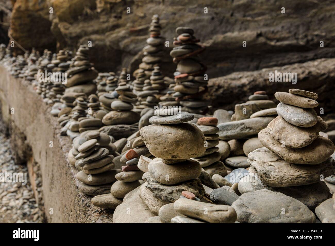 Malerische Nahaufnahme von vielen gestapelten Steinen auf einem auftauchenden Felsen am Eingang des zerklüfteten Kiesstrandes an der Ostküste von Vernazza in... Stockfoto