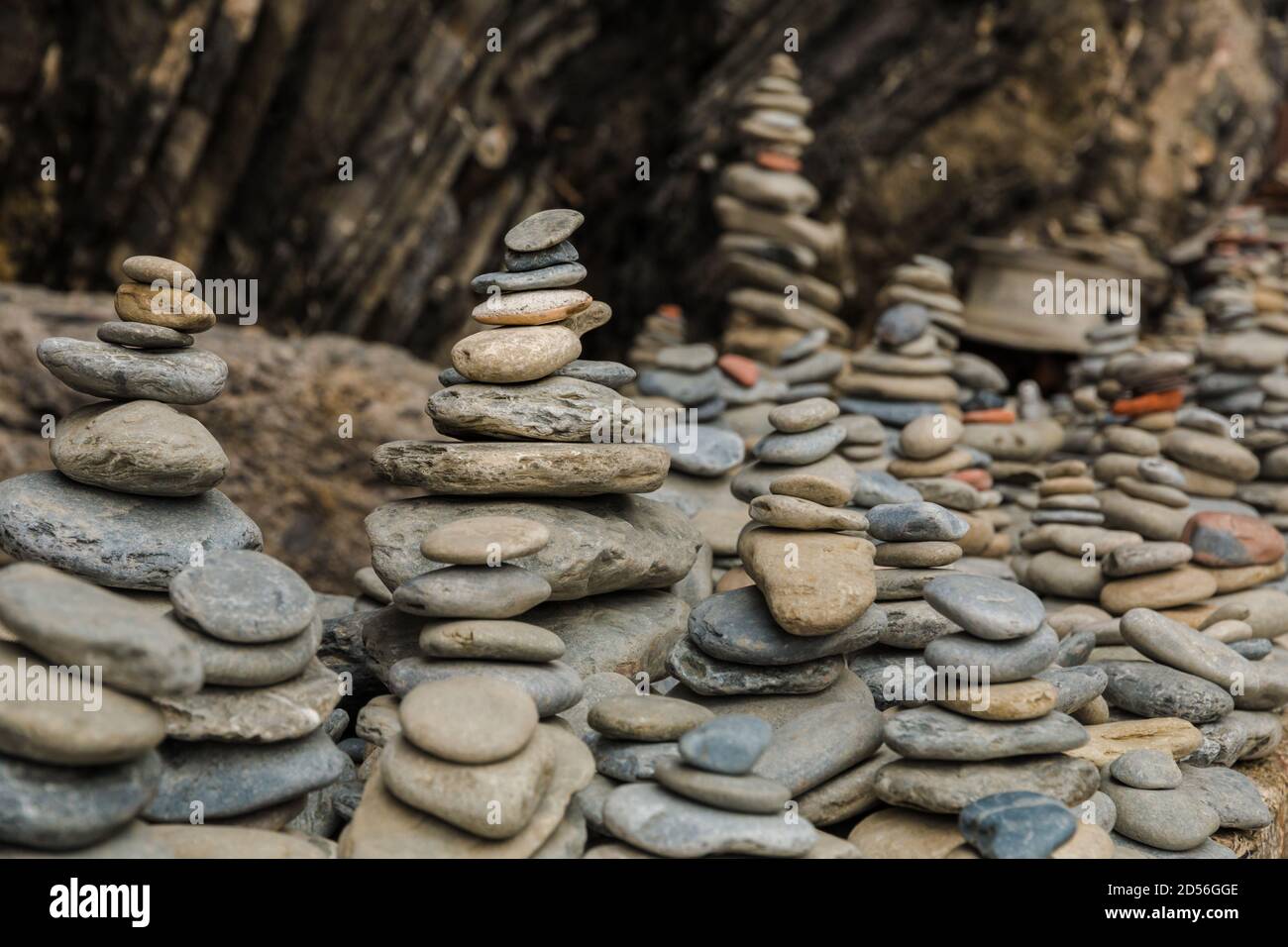 Schöne Nahaufnahme von mehreren gestapelten Steinen in einer Reihe auf einem auftauchenden Felsen am Eingang des zerklüfteten Kiesstrandes an der Ostküste von... Stockfoto