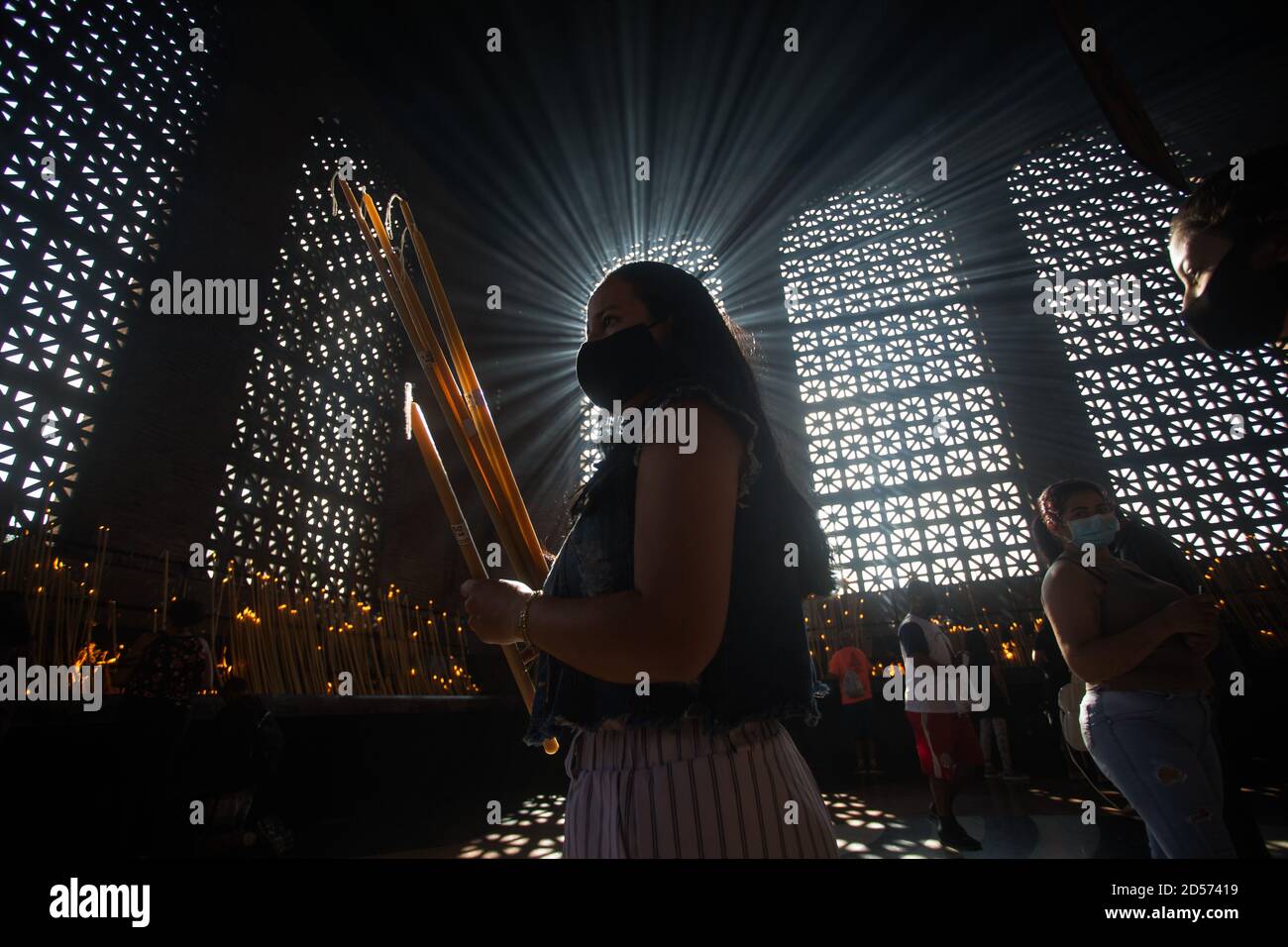 Aparecida, Brasilien. Oktober 2020. Ein Gläubiger trägt Kerzen und betet im Kerzenraum der Basilika von Nossa Senhora Aparecida, während des Tages von Nossa Senhora Aparecida, der schutzpatronin Brasiliens. Zum ersten Mal in der Geschichte der Basilika mussten wegen der Corona-Pandemie die Messen hinter verschlossenen Türen oder in Anwesenheit einer kleinen Anzahl von Menschen gefeiert werden. Quelle: Fernando Souza/dpa/Alamy Live News Stockfoto