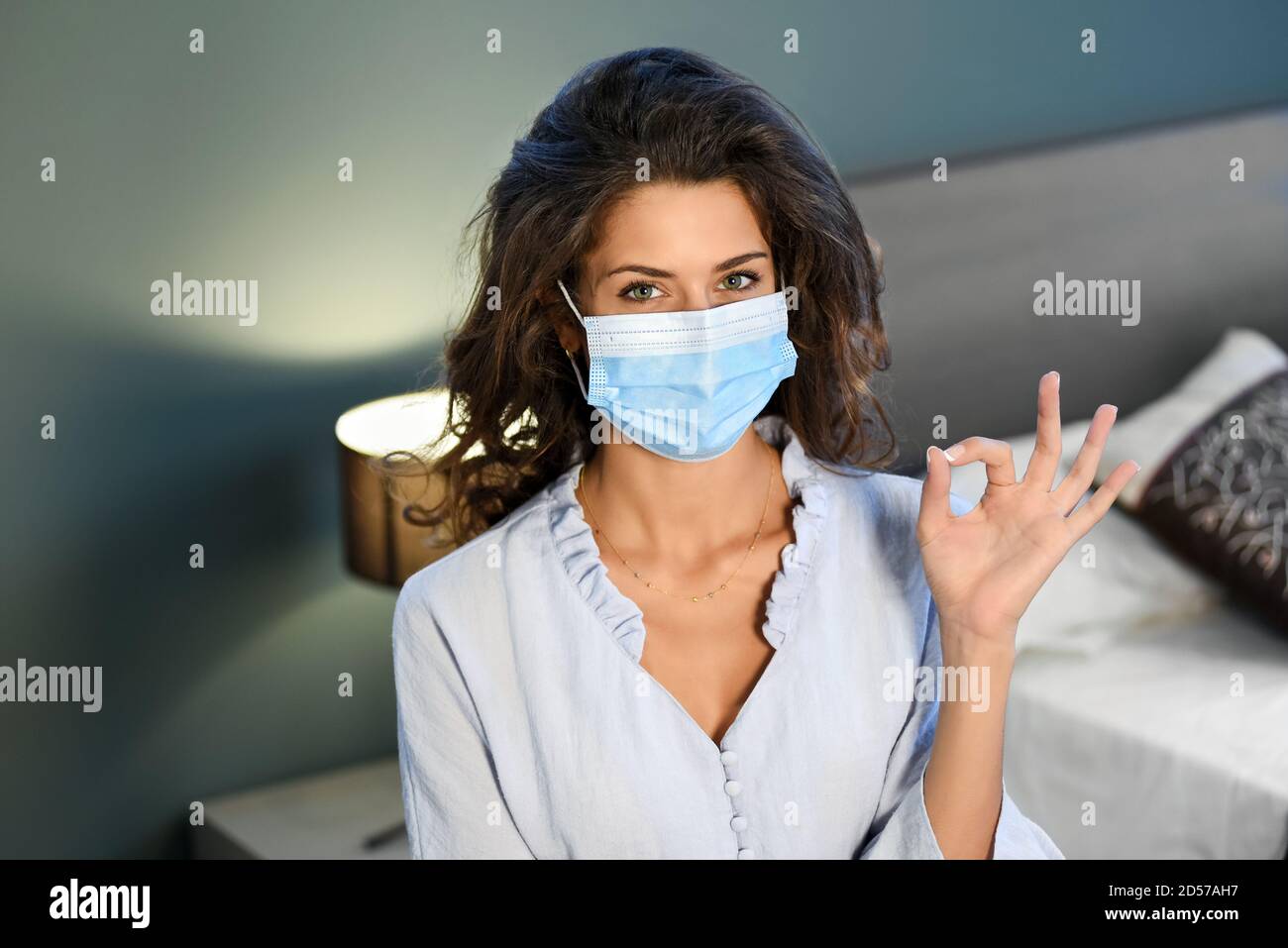 Junge Frau mit einer chirurgischen Gesichtsmaske während der Covid-19 Oder eine Coronavirus-Pandemie, die mit ihrer Hand eine OK-Geste macht In einem Konzept der Neuen Normalität Stockfoto