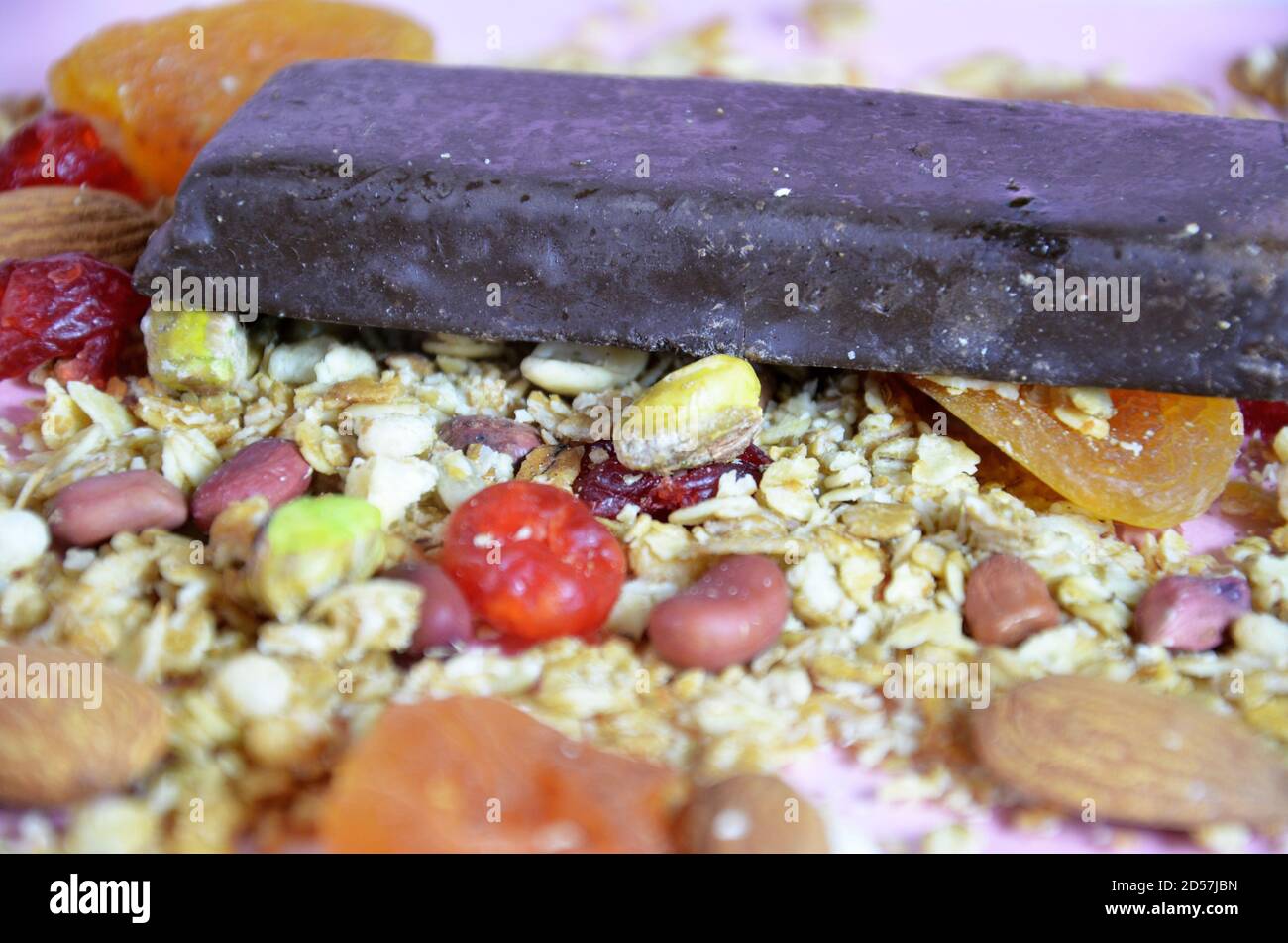 Müsliriegel, Müsliriegel oder Energieriegel mit Hafer, Datteln und Nüssen auf weißem rosa Hintergrund, Nahaufnahme. Snack für Yoga-, Fitness- und Sportbegeisterte Stockfoto