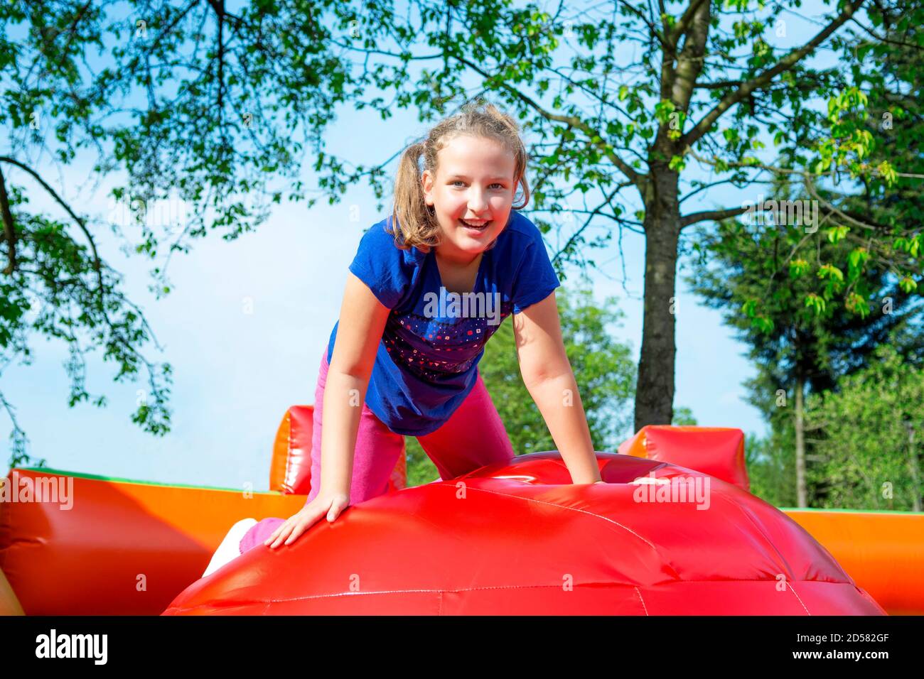 Gerne kleine Mädchen haben viel Spaß beim von Ball zu Ball springen auf ein Schloss aufpumpen. Stockfoto