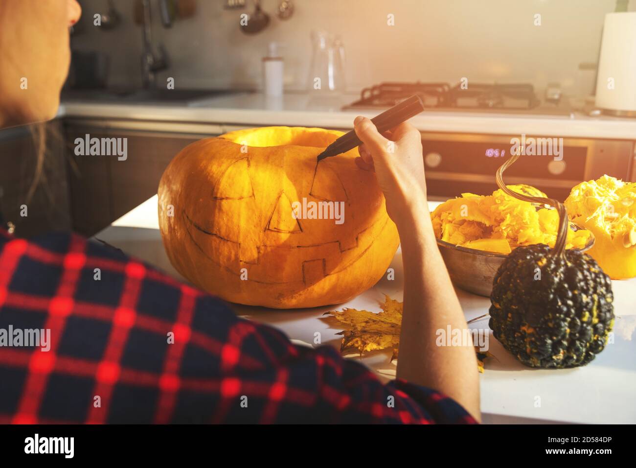 Frau Malerei Gesicht auf halloween Kürbis in der Küche zu Hause Stockfoto