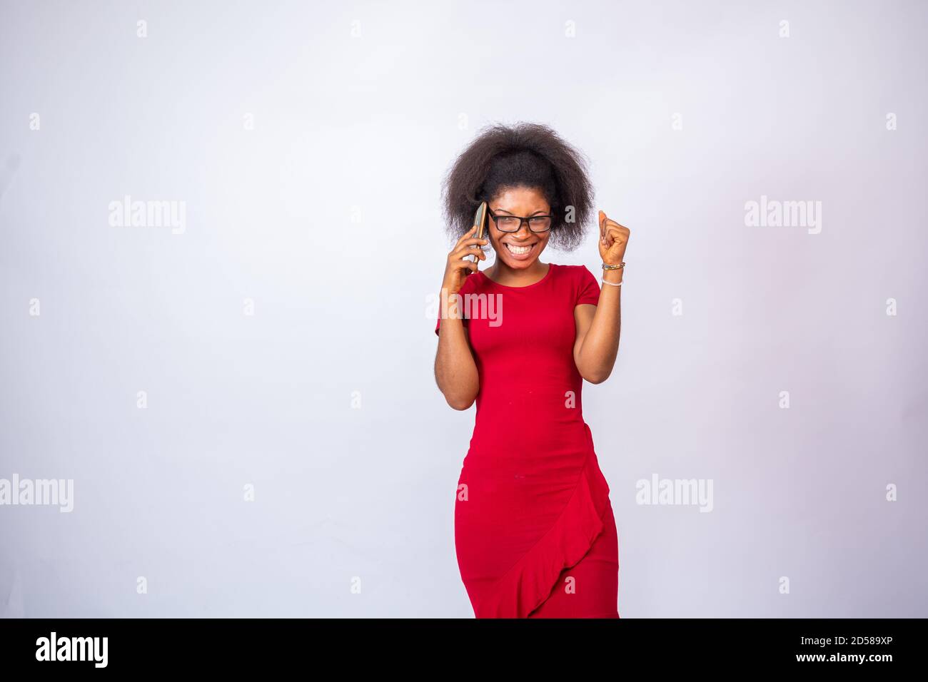 afrikanische Frau trägt ein rotes Kleid und eine Brille machen Telefonanruf fühlt sich aufgeregt Stockfoto