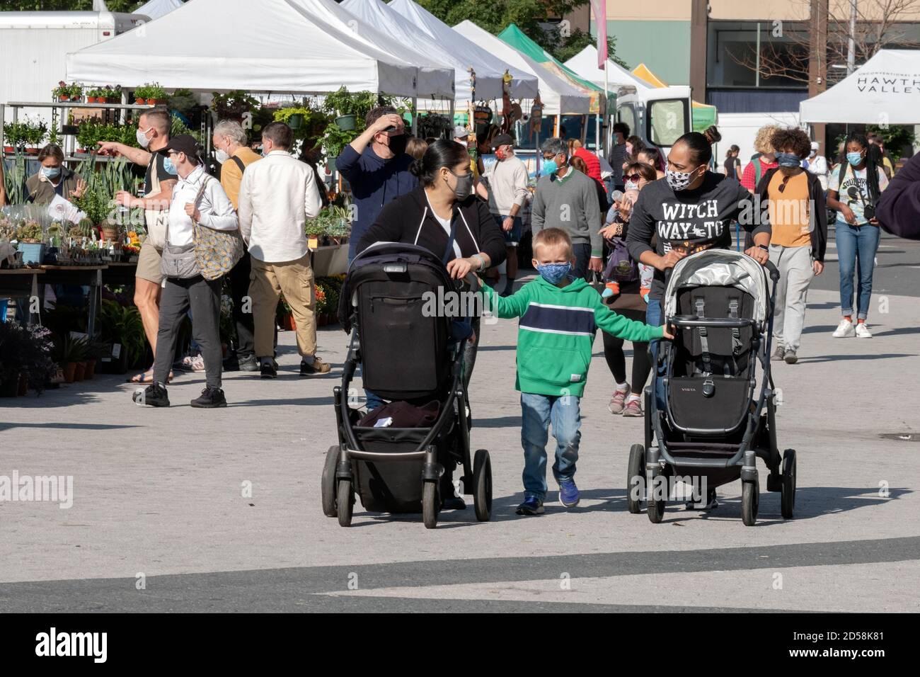 Zwei Frauen schieben Kinderwagen mit einem Kind hält an. Am Union Square Market, wo Masken erforderlich sind. In Manhattan, New York City. Stockfoto