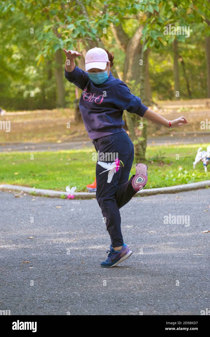 Eine akribische chinesisch-amerikanische Frau, die in einem Park in Queens, New York City, Jianzi spielt. Stockfoto