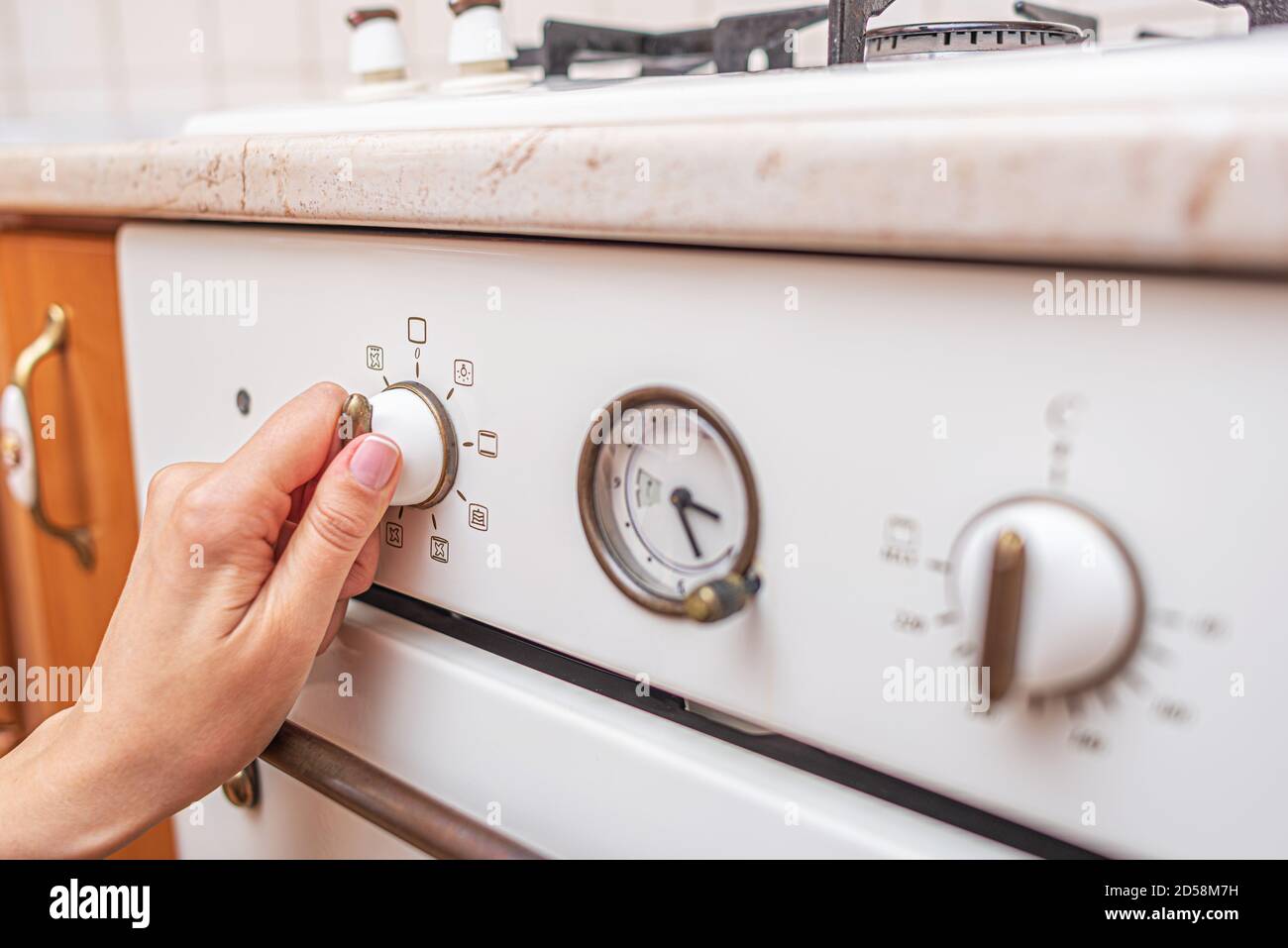Frau benutzt den Ofen zu Hause in der Küche. Stockfoto