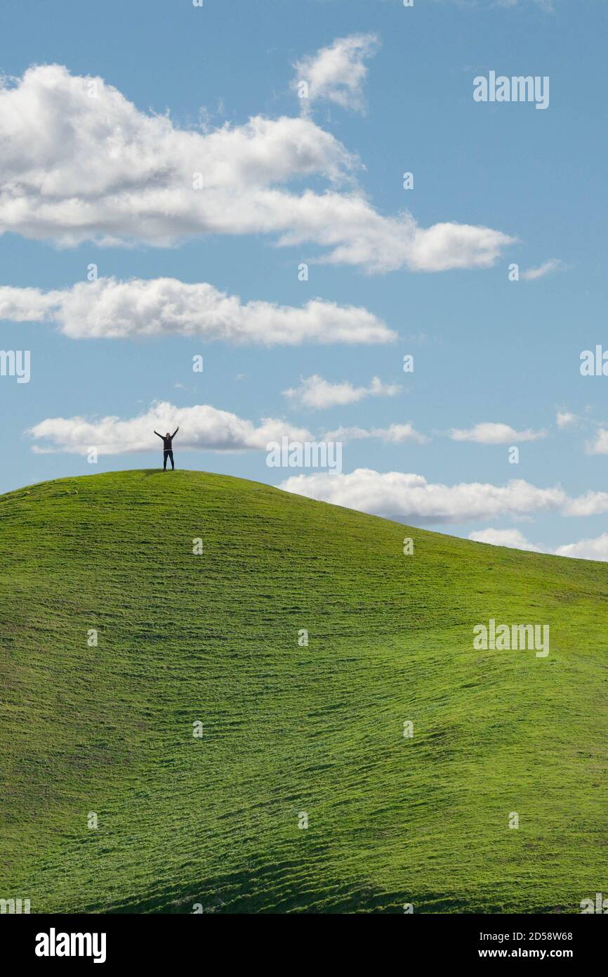 Frau, die auf einem Hügel steht, mit erhobenen Armen zum Himmel, Kalifornien, USA Stockfoto