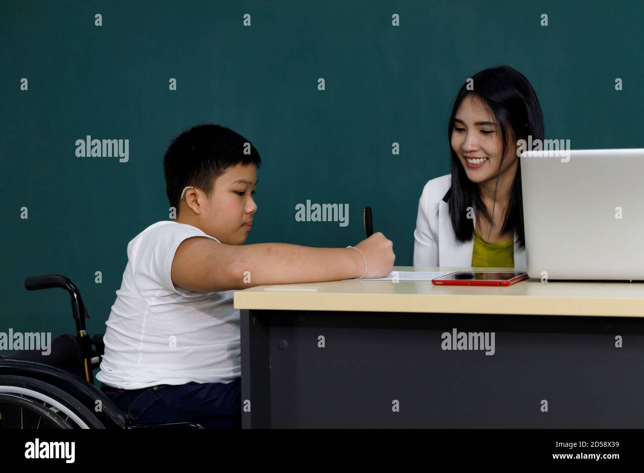 Asiatische deaktivieren junge auf Rollstuhl Studie mit Lehrer im Klassenzimmer. Stockfoto
