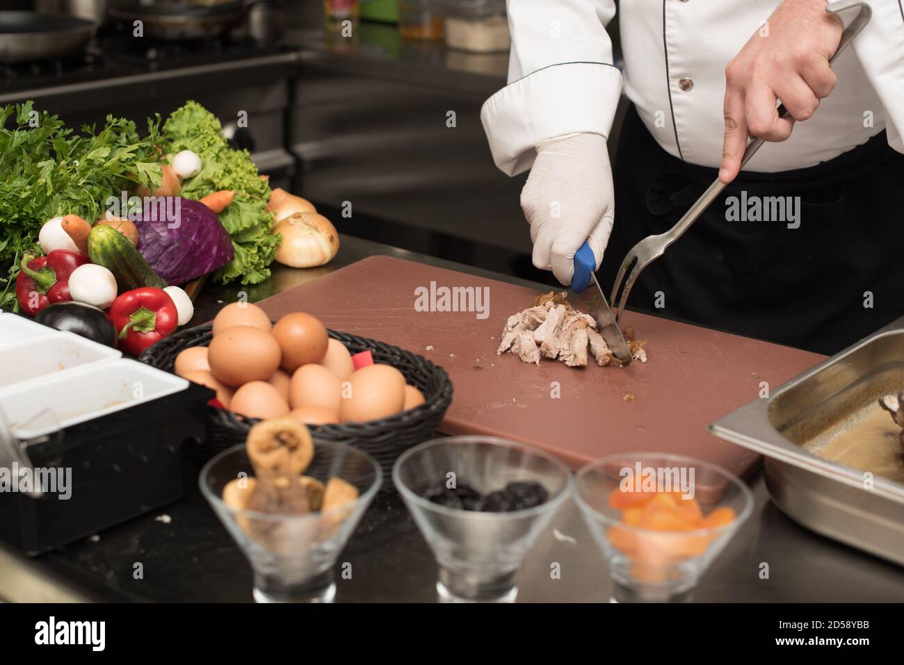 Der Koch schneiden Fleisch auf einem Schneidebrett in einer Küche Stockfoto